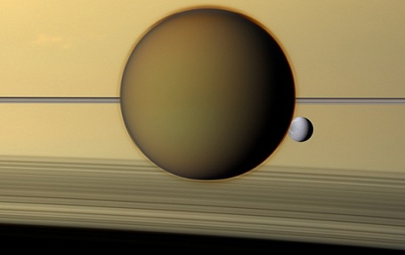 Saturn månerne Titan  og Dione med ringene som baggrund